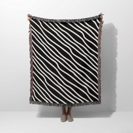 Black and white retro abstract art woven blanket throw tapestry held by a person against a white background