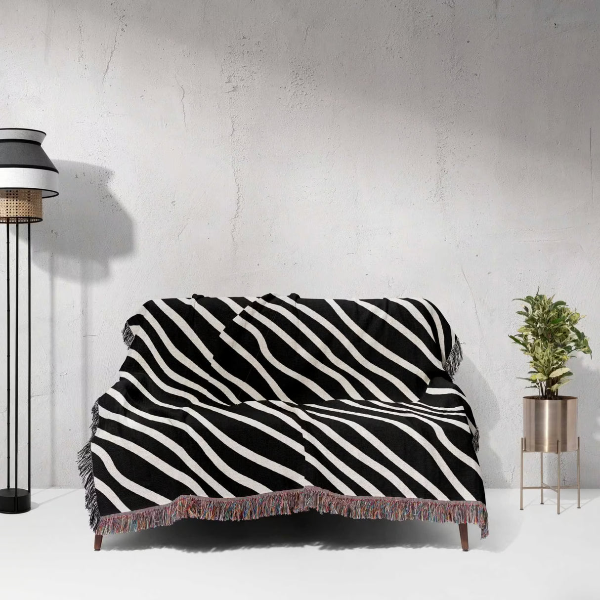 Black and white retro abstract art woven blanket throw tapestry draped over a couch against a white wall.