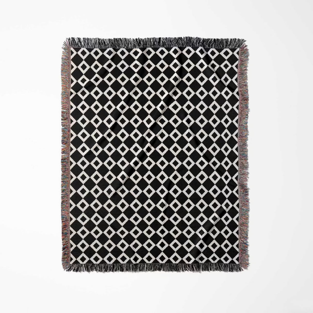 Black and white retro checker woven blanket throw tapestry with fringe full view on a light gray background