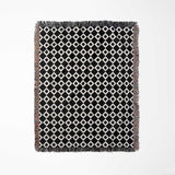 Black and white retro checker woven blanket throw tapestry with fringe full view on a light gray background