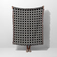 Black and white retro checker woven blanket throw tapestry with fringe held by a person on a white background