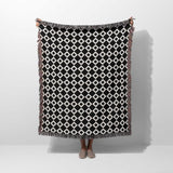 Black and white retro checker woven blanket throw tapestry with fringe held by a person on a white background