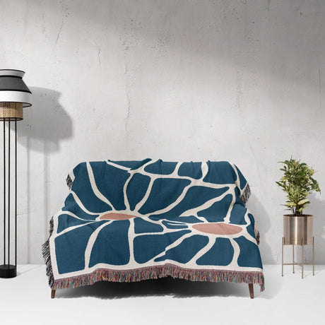Couch with a retro style Matisse inspired tapestry throw blanket for couch against a white wall.