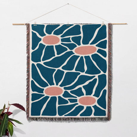 Retro style Matisse inspired tapestry throw blanket for couch with blue and red flowers on a white wall.