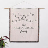 Romantic anniversary custom name blanket with 'The Richardson family' text and heart design hanging on a white wall.