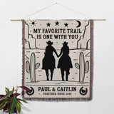 Romantic cowboy and cowgirl cotton anniversary gift – woven throw blanket with cowboy design and text, hanging on a wall.