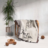 Rustic bull skull cotton anniversary gift woven throw blanket with names branding draped over a chair in a minimalistic room with a plant and decorative items.