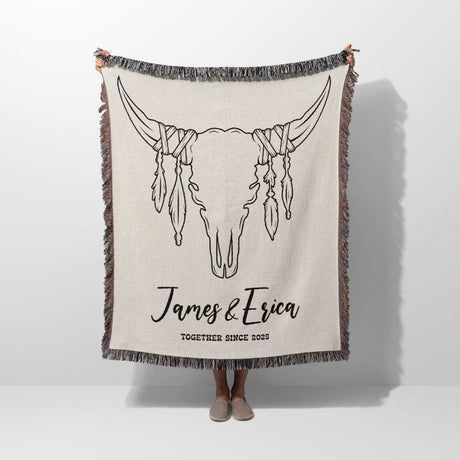 Rustic bull skull cotton anniversary gift woven throw blanket held by a person with bull skull design and personalized text on a white background