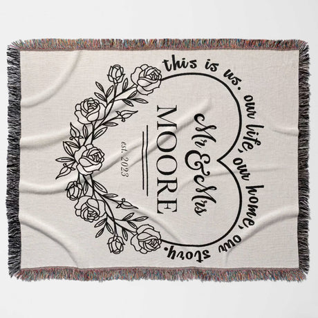 Rustic Mr and Mrs 2nd year anniversary gift woven throw blanket with floral design and text 'this is us, our life, our home, our story. MOORE' on a beige background