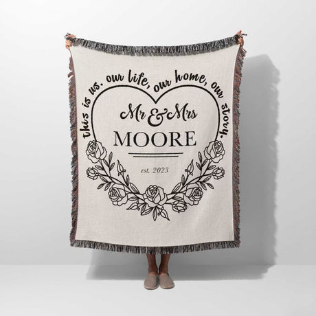 Rustic Mr and Mrs 2nd year anniversary gift woven throw blanket with personalized text and floral design hold by a person on a white background
