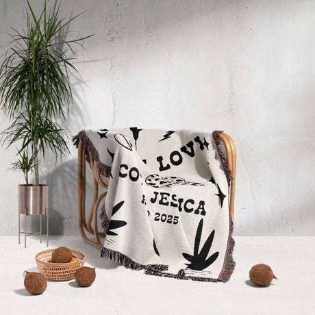 Rustic western cotton anniversary gift woven throw blanket with text and patterns draped over a chair in a room with a plant and decorative items.