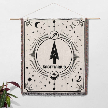 The Sagittarius Zodiac Blanket is displayed as wall art, emphasizing its versatility and aesthetic appeal. The intricate zodiac design and multicolor fringes make it a perfect decorative piece and a thoughtful birthday gift for women and men interested in astrology.