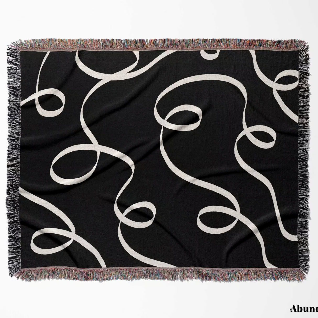 Black and white scribble lined woven blanket throw with fringe flat lay on a plain background.