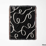 Black and white scribble lined woven blanket throw with fringe full view on a white background.