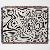 Simple black and white modern couch woven throw blanket with black and white abstract pattern on a beige background