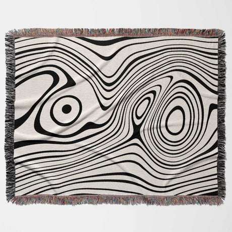 Simple black and white modern couch woven throw blanket with black and white abstract pattern on a beige background