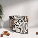 Simple black and white modern couch woven throw blanket draped over a chair with a minimal background