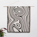 Simple black and white modern couch woven throw blanket as Woven tapestry with black and white abstract pattern hanging on a white wall.
