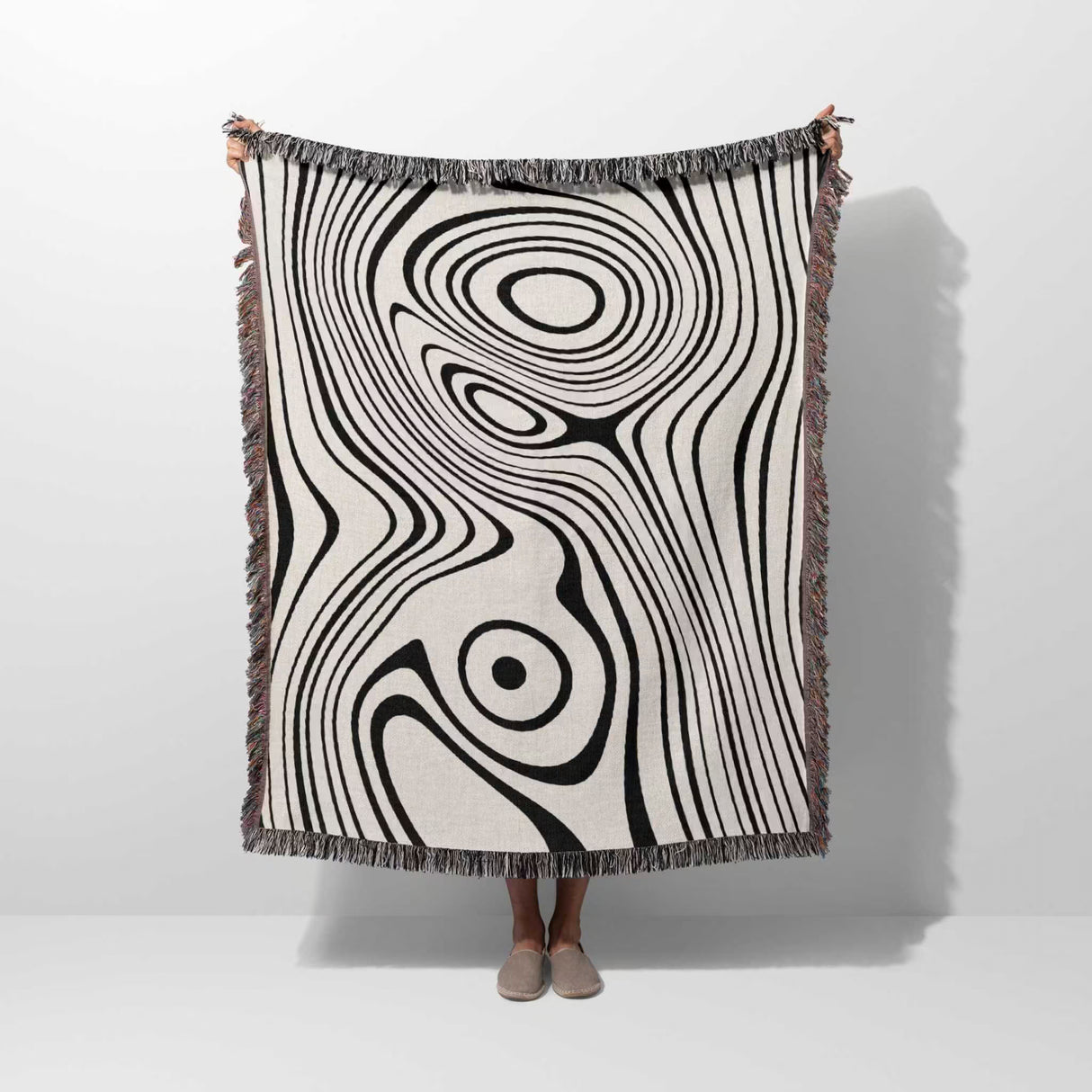 Person holding a simple black and white modern couch woven throw blanket against a white background