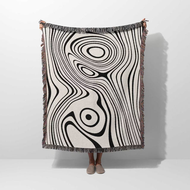 Person holding a simple black and white modern couch woven throw blanket against a white background