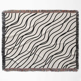 Black and white simple curly lines woven blanket throw full view on a beige background.