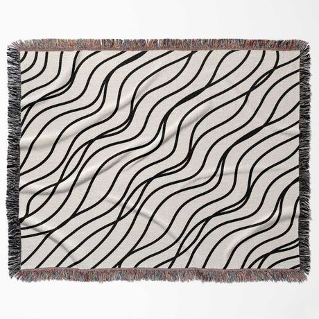 Black and white simple curly lines woven blanket throw full view on a beige background.
