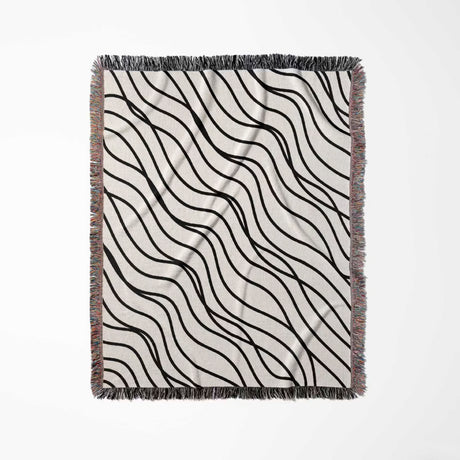 Black and white simple curly lines woven blanket throw flat lay on a white background.