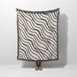 Person holding a black and white simple curly lines woven blanket throw against a white background.