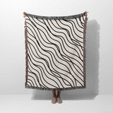 Person holding a black and white simple curly lines woven blanket throw against a white background.