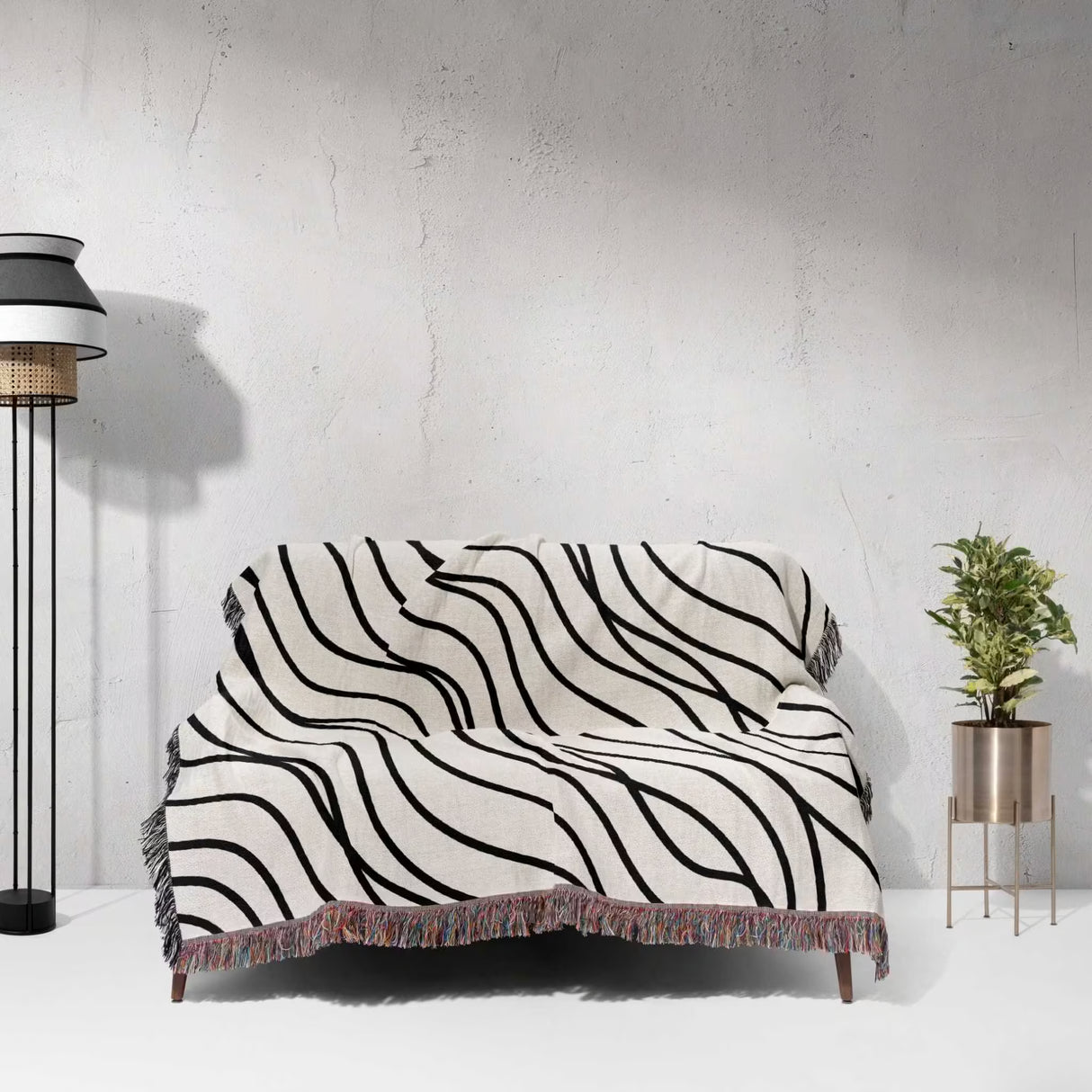 Black and white simple curly lines woven blanket throw on a sofa against a white wall.