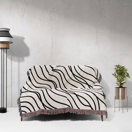 Black and white simple curly lines woven blanket throw on a sofa against a white wall.