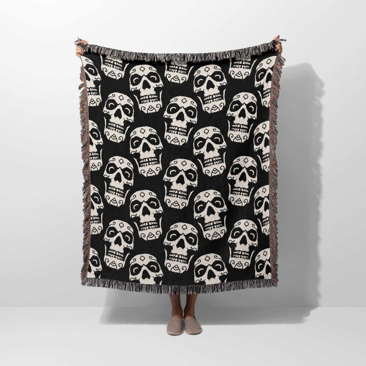Black and white patterned throw blanket draped over a person on a white background