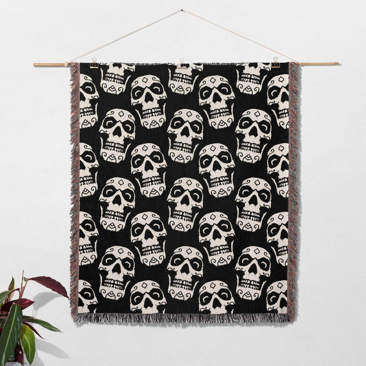 Black and white geometric patterned blanket hanging on a wooden rod against a white background.