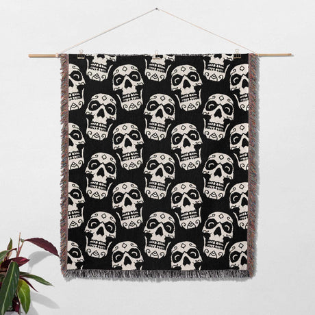 Black and white geometric patterned blanket hanging on a wooden rod against a white background.