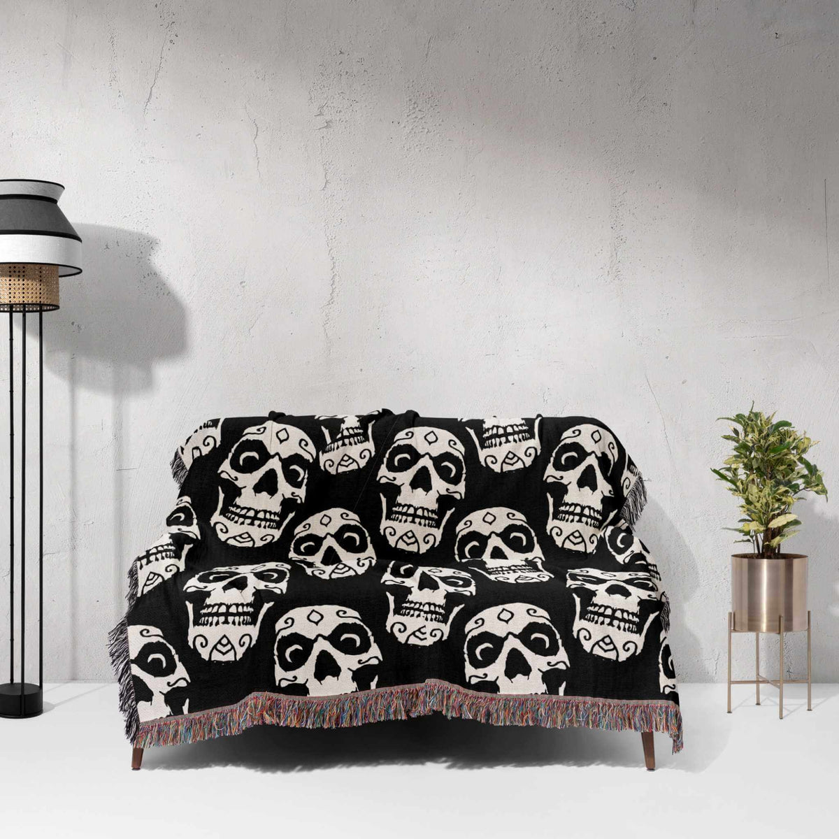 Black blanket with white skull patterns draped over a sofa against a light gray wall.