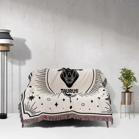 The Taurus Zodiac Blanket spread over a couch, highlighting its intricate woven design and celestial motifs. Ideal for adding a unique touch to home decor and as a special birthday gift for astrology enthusiasts.