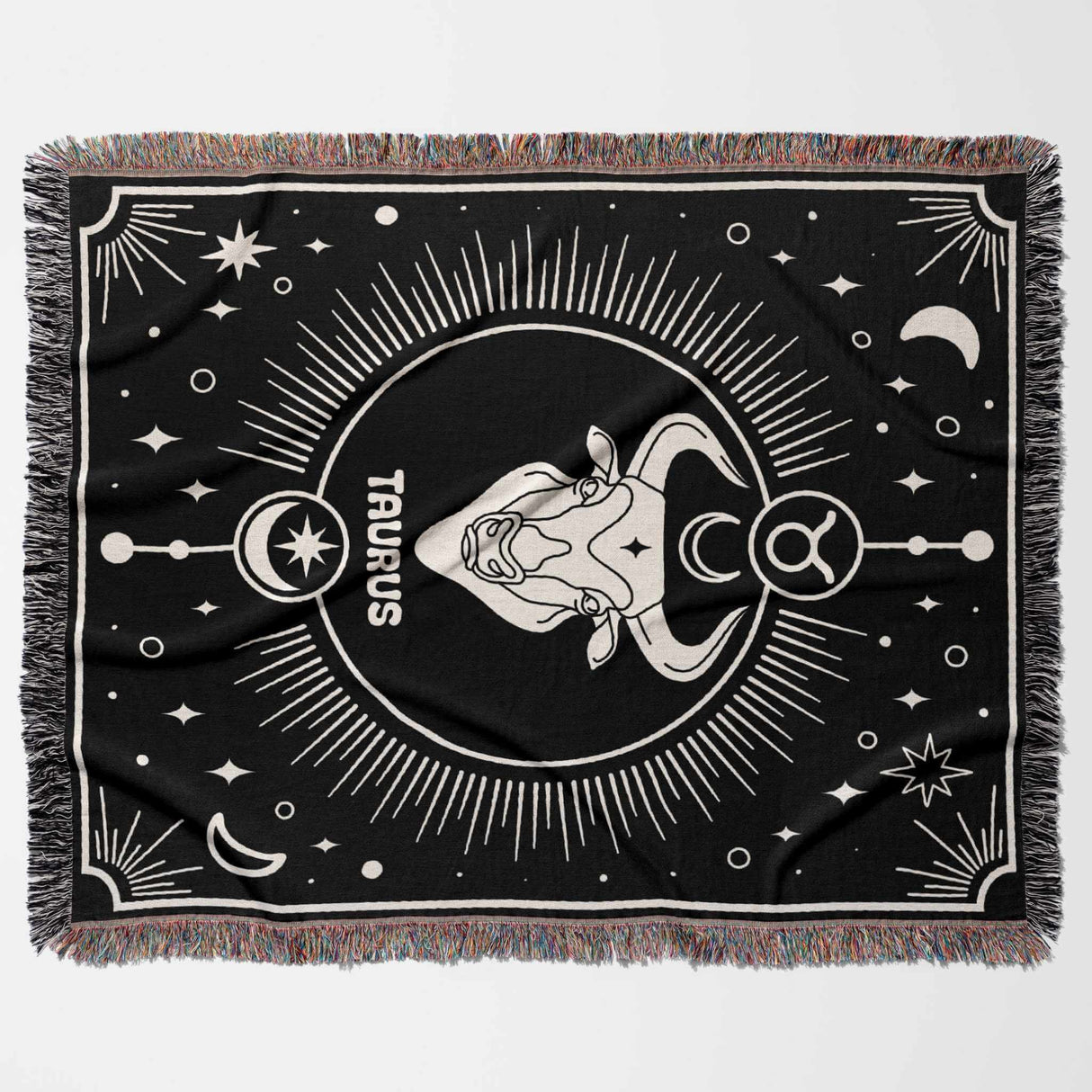 Flat horizontal view of the Taurus Zodiac Blanket displaying the full design. The black and white woven throw blanket features the Taurus zodiac symbol and bull head in the center, surrounded by celestial elements and a multicolor fringe.