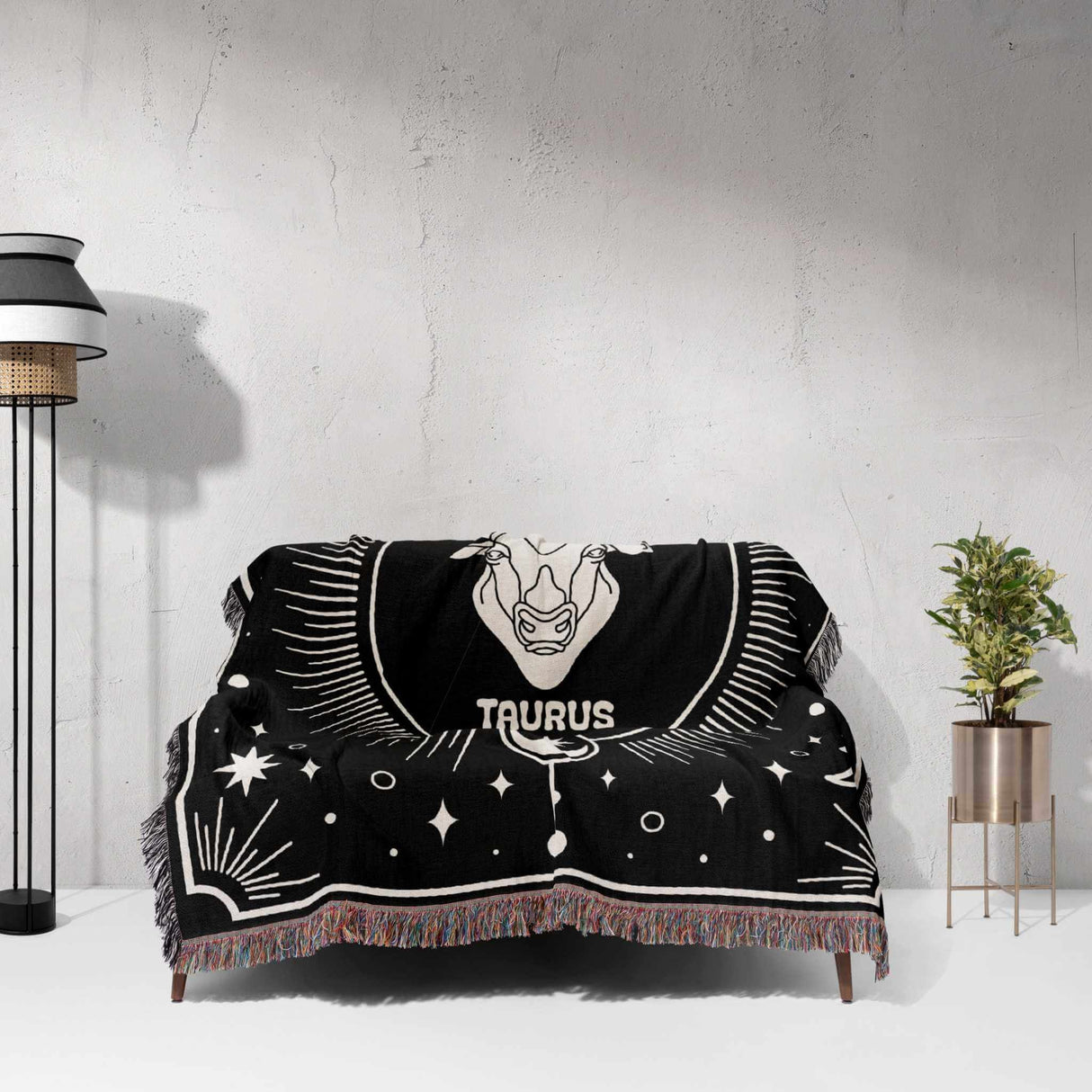 Taurus Zodiac Blanket elegantly spread over a couch. The black and white woven throw blanket features the Taurus symbol and celestial motifs, creating a stylish and comfortable atmosphere.