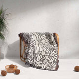 Wooden chair with a black and white topographic map design woven throw blanket draped over it on a light background.