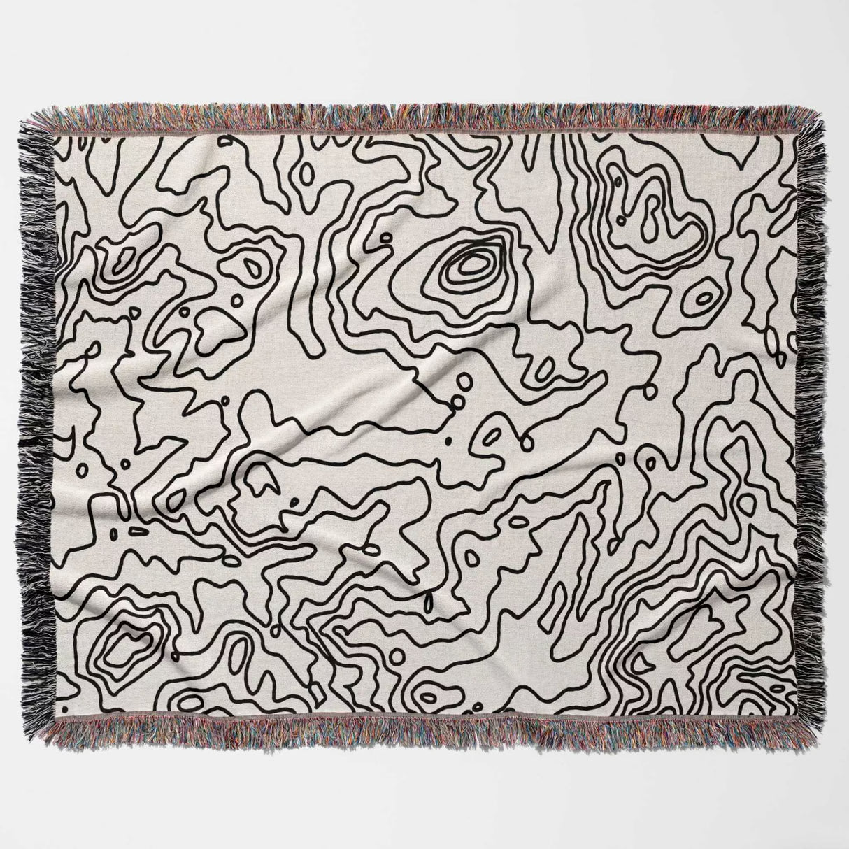 Black and white topographic map design woven throw blanket with black line art pattern flat lay on a light background.