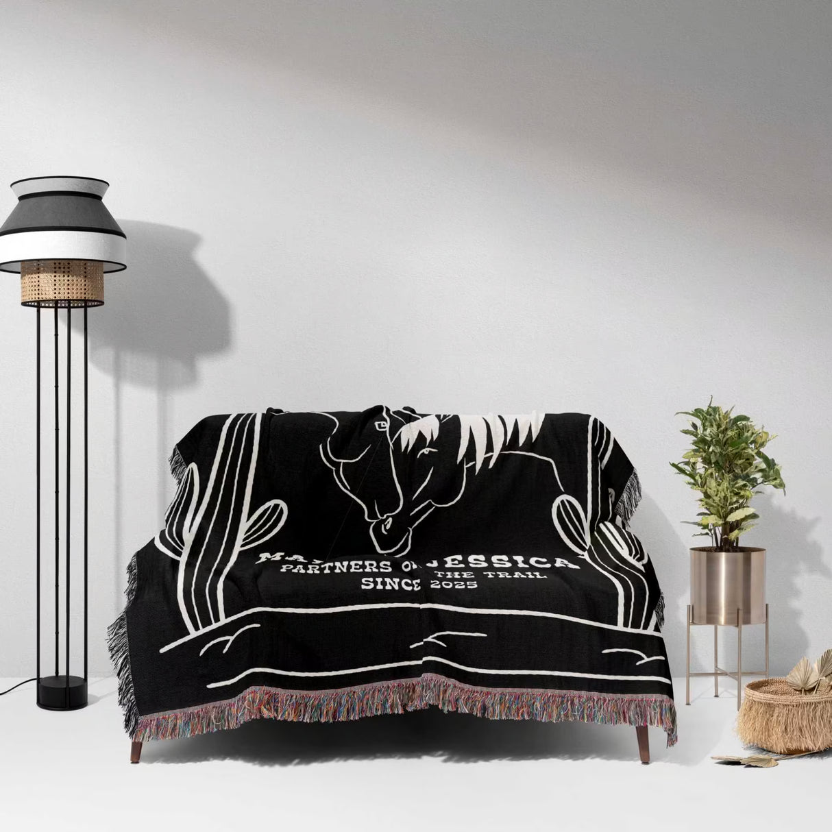 Two horses 2nd anniversary gift woven throw blanket with white horse design draped over a couch in a room with a lamp and plant.