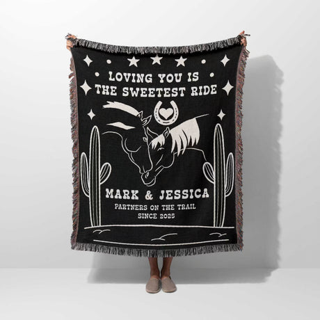 Two horses 2nd anniversary gift woven throw blanket with white text and graphics, featuring a horse and cactus design, held by a person.