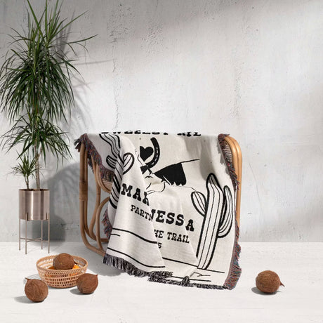 Two horses woven throw blanket cotton anniversary gift with text and graphics draped over a chair in a room with a plant and decorative items.