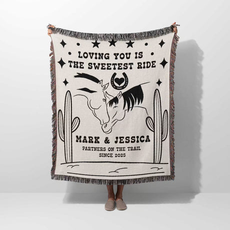 Two horses woven throw blanket cotton anniversary gift with horse design and text held by a person on a white background