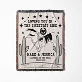 Two horses woven throw blanket cotton anniversary gift full view with horses and cactus design, text 'Loving you is the sweetest ride' and personalized names.