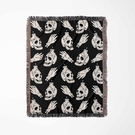 Black blanket with white skull and hand designs on a white background