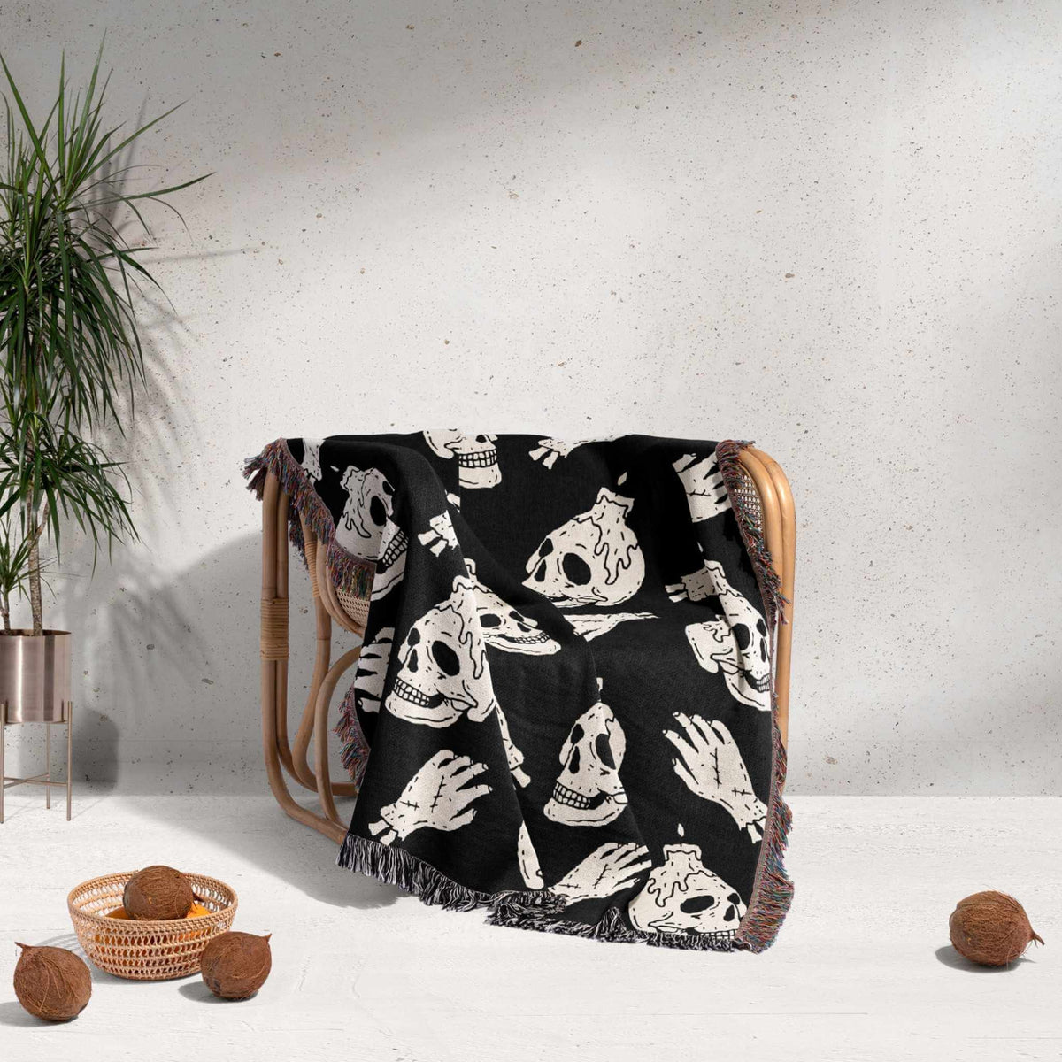 Black blanket with white skull designs draped over a chair against a light gray wall.