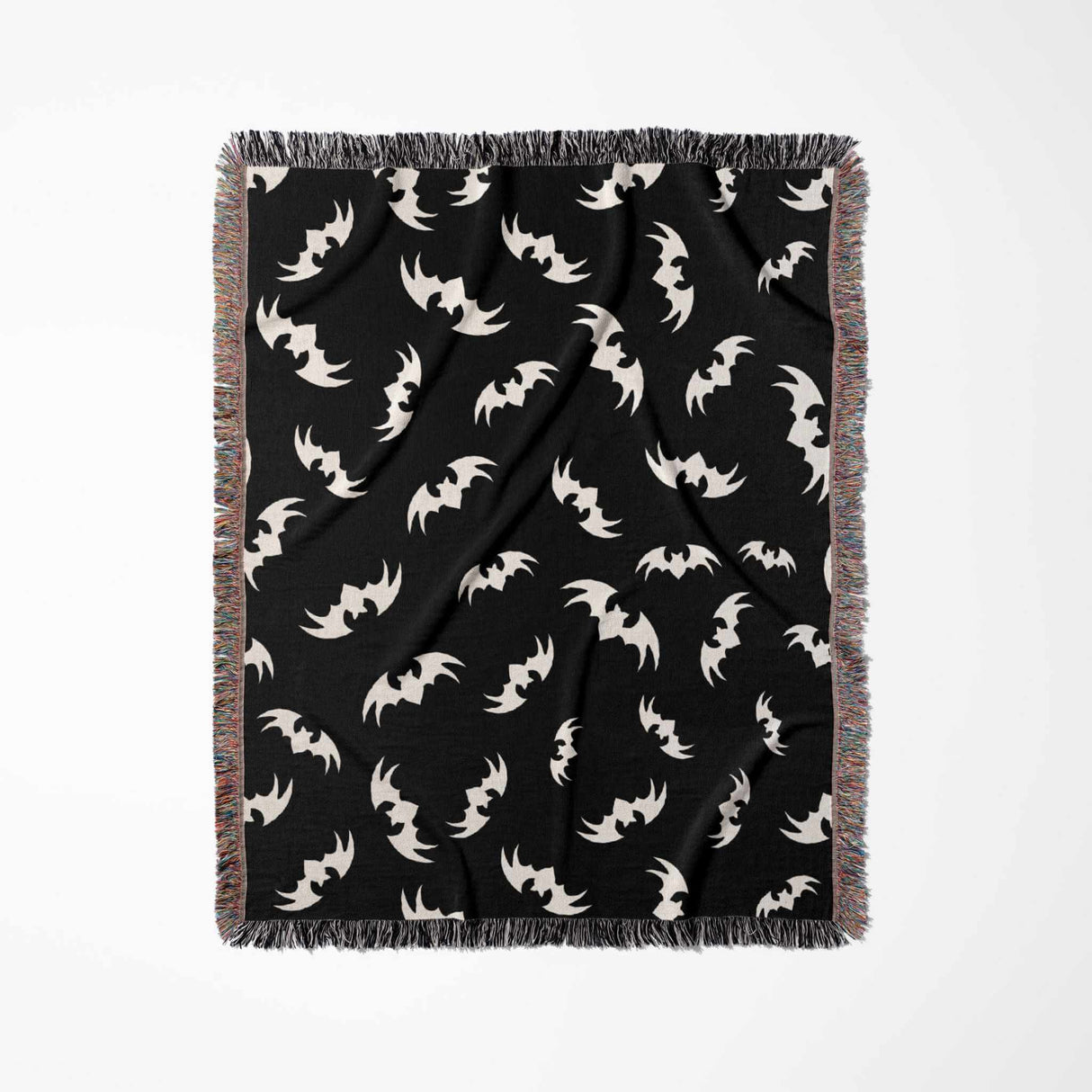 The blanket is shown flat vertically, displaying the repeating bat motif in an organized, symmetrical arrangement across the dark fabric. The texture and quality of the weave are evident, with the multicolored fringe running along the edges, creating a striking contrast.