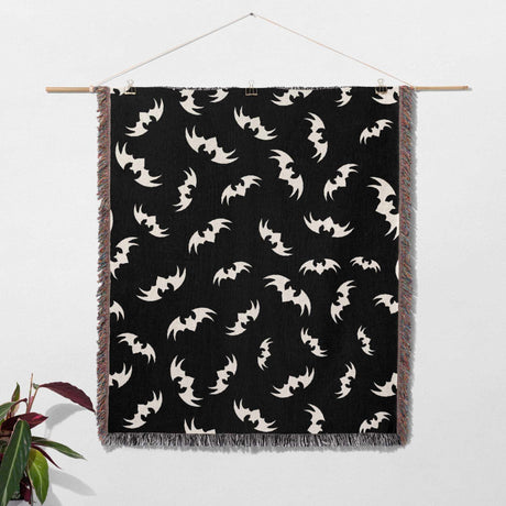 The Halloween blanket is hung on a wall as a tapestry, turning it into a piece of wall art. The bats pattern creates a spooky atmosphere, while the multicolored fringe along the bottom edge adds a decorative element. This image highlights the blanket's versatility as both a functional and decorative item.