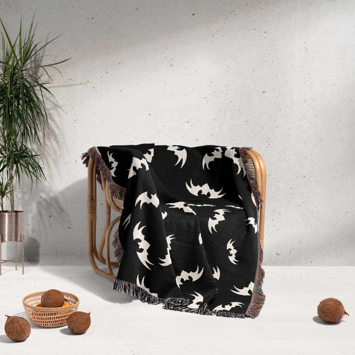 In this image, the Halloween-themed blanket is casually draped over a chair, showcasing its decorative appeal. The bats pattern is clearly visible, and the multicolored fringe adds a playful touch, making it an ideal accent for any Halloween-themed decor.